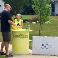 Child serving lemonade from a FunDeco Lemonade Stand