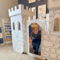 Boy playing in cardboard castle.